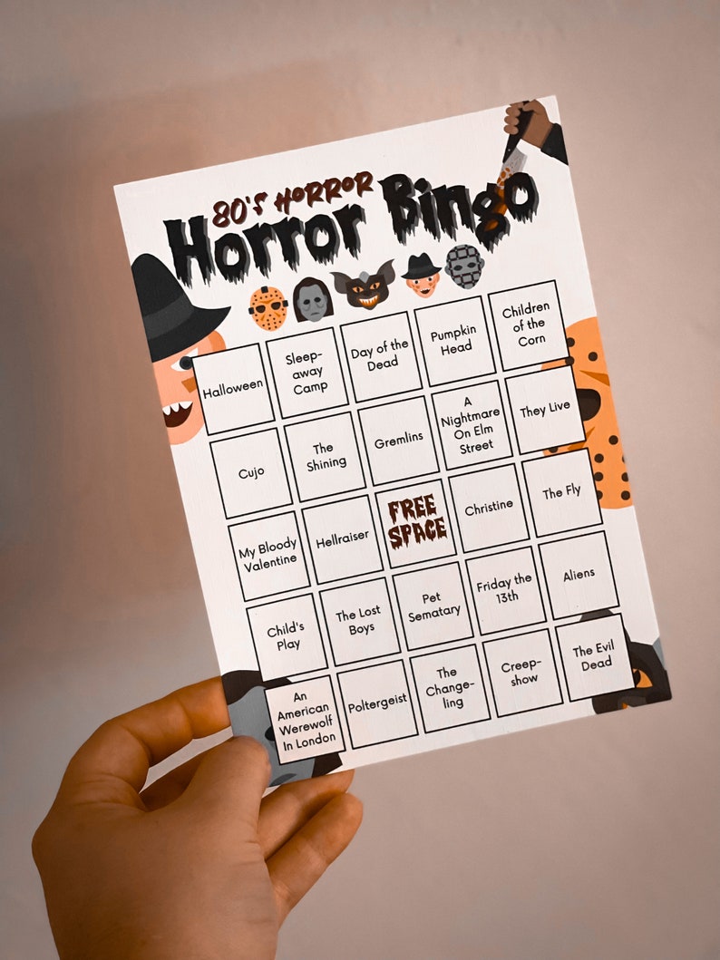 May include: A white 80's Horror Bingo card with a black border. The card features a witch, a knife, and various horror movie icons. The bingo card includes titles like "Halloween", "Gremlins", and "Friday the 13th".