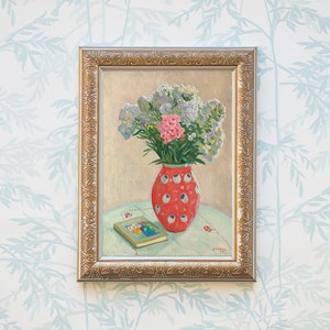 Peut inclure: Une peinture encadr&eacute;e repr&eacute;sentant un bouquet de fleurs violettes et roses dans un vase &agrave; pois rouges et blancs. Le vase est pos&eacute; sur une table avec un livre.