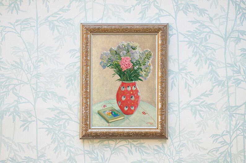 Peut inclure: Une peinture encadr&eacute;e repr&eacute;sentant un bouquet de fleurs violettes et roses dans un vase &agrave; pois rouges et blancs. Le vase est pos&eacute; sur une table avec un livre.
