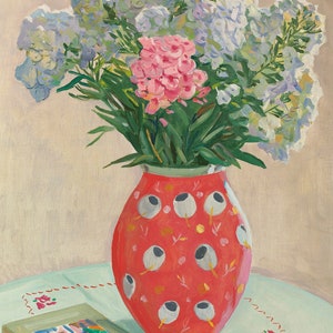 Peut inclure: Un bouquet de fleurs roses et blanches dans un vase rouge &agrave; motifs blancs et gris. Le vase est pos&eacute; sur une nappe bleu clair avec un motif brod&eacute; rouge. Un livre avec une illustration color&eacute;e est sur la table.