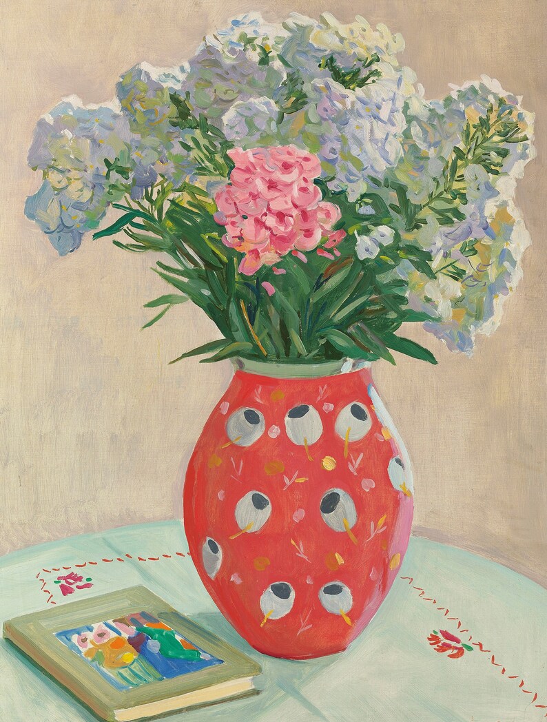 Peut inclure: Un bouquet de fleurs roses et blanches dans un vase rouge &agrave; motifs blancs et gris. Le vase est pos&eacute; sur une nappe bleu clair avec un motif brod&eacute; rouge. Un livre avec une illustration color&eacute;e est sur la table.