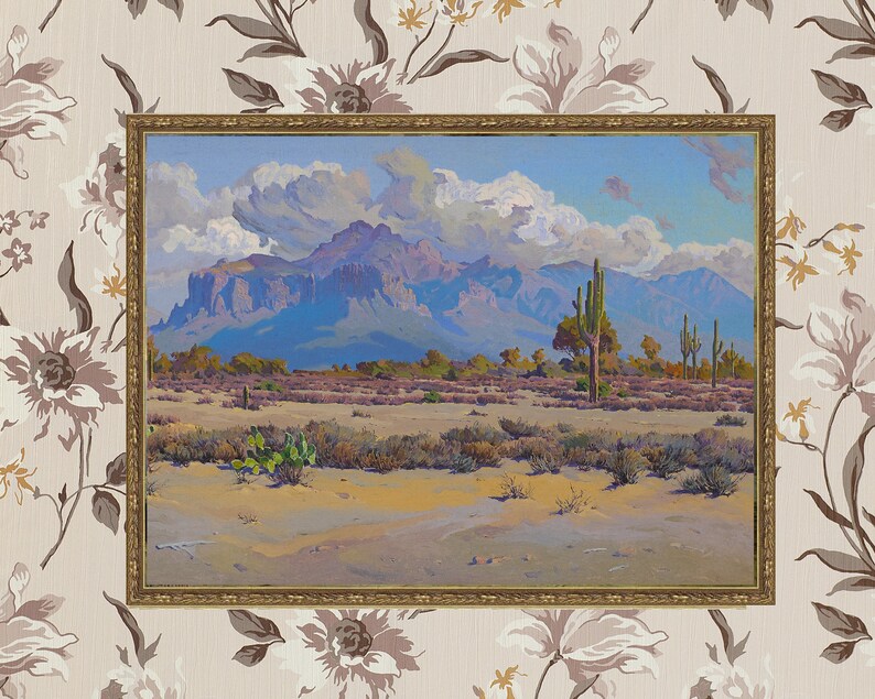 Puede incluir: Una pintura al &oacute;leo enmarcada que representa un paisaje des&eacute;rtico con monta&ntilde;as en el fondo. En primer plano se pueden ver varias plantas del desierto, incluyendo cactus y arbustos. El cielo es de un azul brillante con nubes blancas y esponjosas.