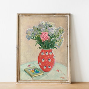 Peut inclure: Une peinture encadr&eacute;e repr&eacute;sentant un bouquet de fleurs roses et bleues dans un vase &agrave; motifs rouge et blanc sur une table avec un livre. La peinture est sign&eacute;e et dat&eacute;e.