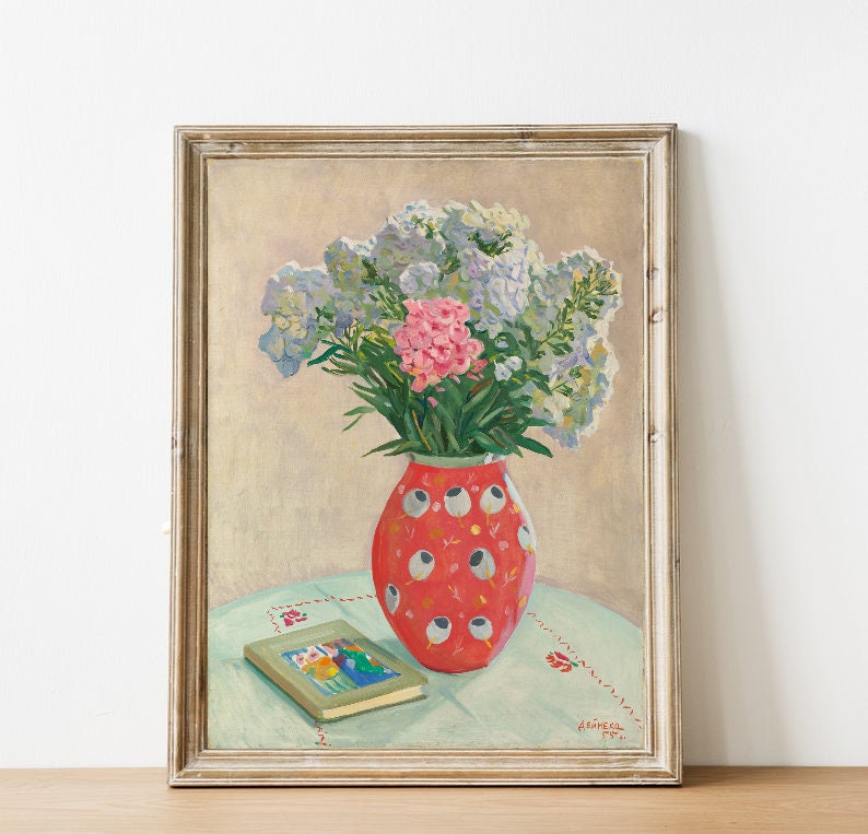 Peut inclure: Une peinture encadr&eacute;e repr&eacute;sentant un bouquet de fleurs roses et bleues dans un vase &agrave; motifs rouge et blanc sur une table avec un livre. La peinture est sign&eacute;e et dat&eacute;e.