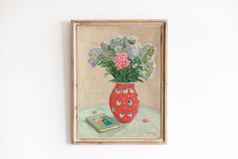 Peut inclure: Une peinture encadr&eacute;e repr&eacute;sentant une nature morte avec un bouquet de fleurs roses et violettes dans un vase &agrave; motifs rouge et blanc. Le vase est pos&eacute; sur une nappe bleu clair avec un livre sur la table.
