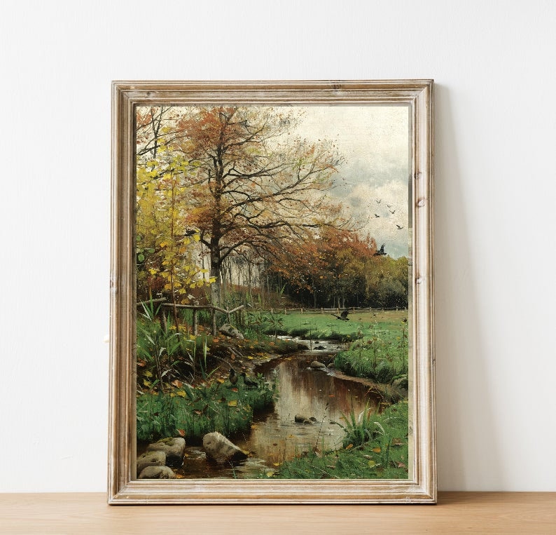 May include: A framed painting depicting a stream flowing through a forest in autumn. The trees have yellow and orange leaves, and the water is reflecting the sky. There are birds flying in the sky.