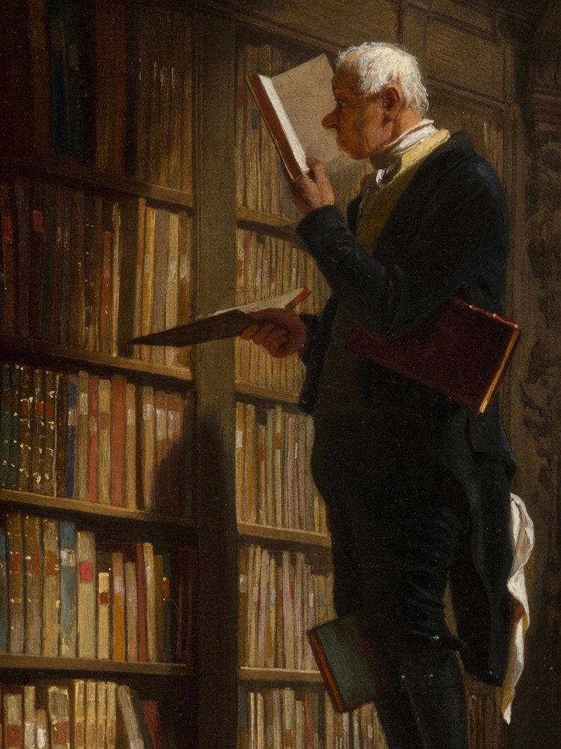 May include: A man in a dark suit and white shirt stands in a library, holding a book in his left hand and looking at another book in his right hand. The library shelves are filled with books.