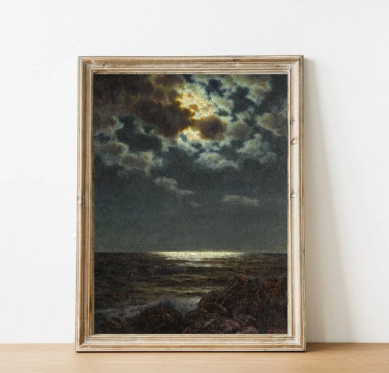 May include: A framed painting depicting a seascape at night, with a full moon shining through dark clouds. The moon's light is reflected on the water, creating a shimmering effect. The painting is in a rustic wooden frame.