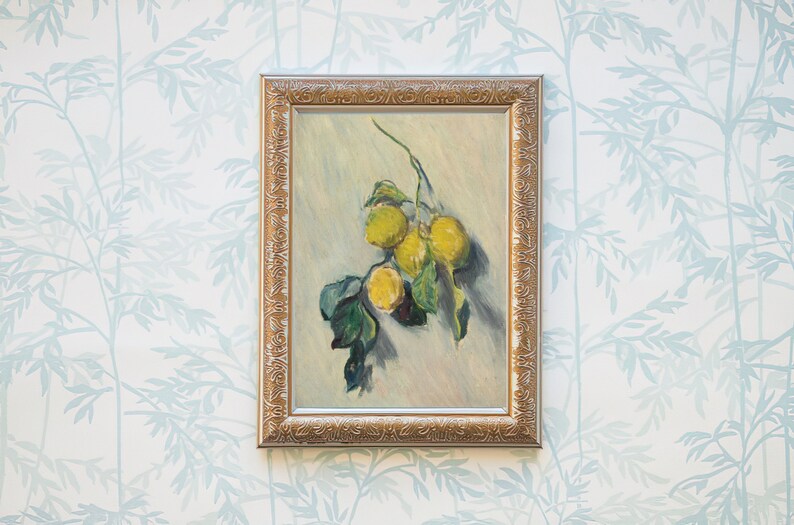 May include: A framed painting depicting a still life of lemons on a branch. The lemons are yellow and the branch has green leaves. The painting is set against a white background with a light blue floral pattern.