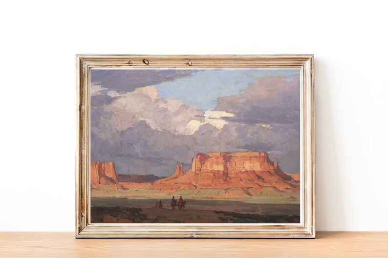 May include: A framed painting depicting a desert landscape with red rock formations and a cloudy sky. Three figures on horseback are visible in the distance.