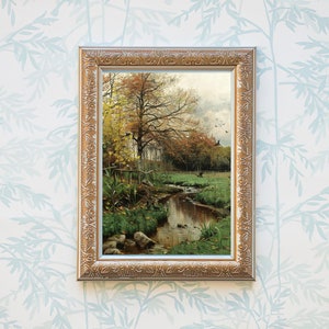May include: A framed painting of a stream running through a forest in autumn. The trees are mostly yellow and orange, with some green leaves still remaining. The stream is clear and reflects the sky and trees. There are a few rocks in the stream.