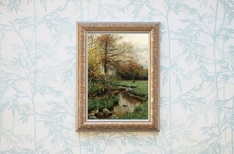 May include: A framed painting of a stream running through a forest in autumn. The trees are mostly yellow and orange, with some green leaves still remaining. The stream is clear and reflects the sky and trees. There are a few rocks in the stream.