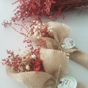 May include: Two small bouquets of dried flowers wrapped in burlap fabric. The bouquets are tied with twine and have a small round tag attached with the text "Tara & Kyle" and "Savie & Always 5.27.2017".