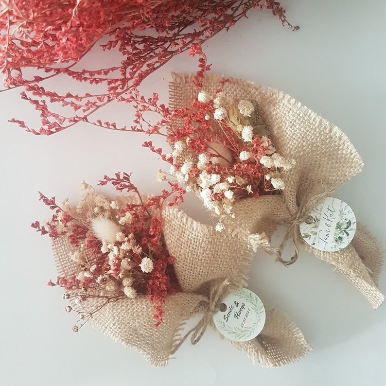 May include: Two small bouquets of dried flowers wrapped in burlap fabric with twine and a circular tag. The tags have handwritten text, one says "Save the Date" and the other says "Jane & Matt".