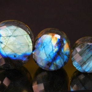 Peut inclure: Trois bouchons ronds en labradorite, une pierre précieuse irisée, dans différentes nuances de bleu, vert et blanc. Les bouchons sont facetés et ont une finition lisse et polie.