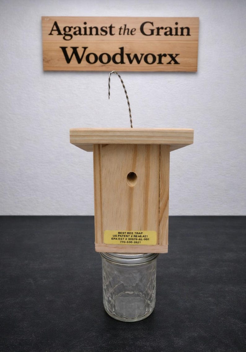 Puede incluir: Una trampa para abejas de madera clara con un orificio circular y un alambre met&aacute;lico para colgar. Un frasco de vidrio transparente est&aacute; sujeto en la parte inferior. Una etiqueta amarilla dice: BEST BEE TRAP US PATENT # RE48,421 EPA EST # 00079-AL-001 770-530-2621.