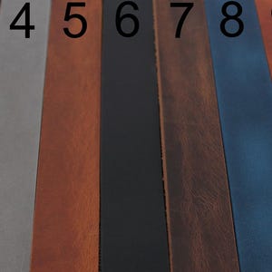 May include: Eleven vertical leather strips arranged side-by-side, numbered 1 through 11. The colours include various shades of brown, grey, black, blue, orange, and green. Each strip has a smooth, flat surface and a consistent rectangular shape.