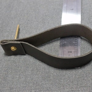 May include: A dark grey leather loop handle secured with a brass screw and fastener. A metal ruler is positioned behind the loop, showing the handle measures approximately 9 cm in length from the screw to the outer edge of the loop.