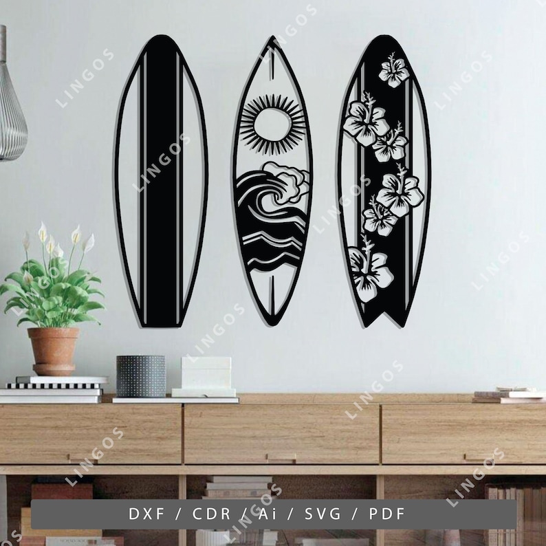 K&ouml;nnte beinhalten: Drei schwarze und wei&szlig;e Surfboard-Wanddekorationen. Die Surfboards sind mit einer Sonne, Wellen und Hibiskusbl&uuml;ten verziert.