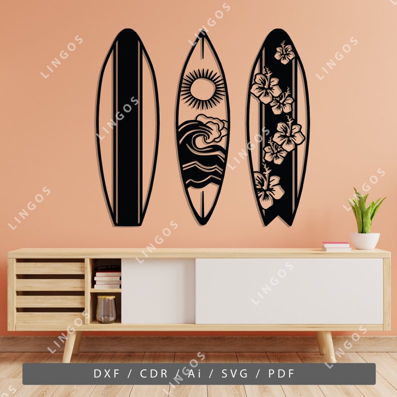 K&ouml;nnte beinhalten: Drei schwarze Wanddekorationen in Form von Surfbrettern mit verschiedenen Designs. Das linke Surfbrett ist schlicht, das mittlere Surfbrett hat ein Sonnen-, Wellen- und Wolken-Design und das rechte Surfbrett hat ein florales Design.