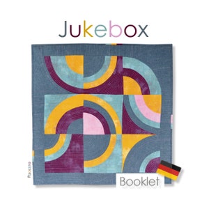 Könnte beinhalten: Ein Quiltmuster namens "Jukebox" mit einem geometrischen Design aus gelbem, blauem, rosa und violettem Stoff. Das Quiltmuster enthält den Text "Booklet" und eine kleine deutsche Flagge.