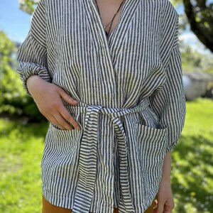 Puede incluir: Una bata de lino a rayas blancas y negras con cintur&oacute;n de anudar. La bata tiene un corte holgado y es perfecta para relajarse en casa.