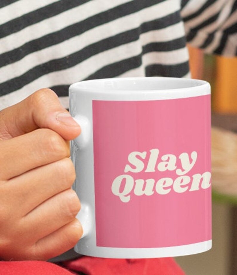 May include: White ceramic mug with a pink background and the text "Slay Queen" in a retro font.
