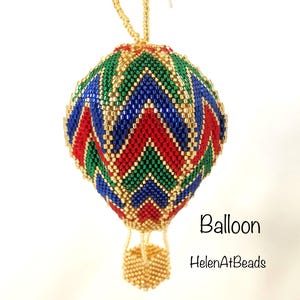May include: A beaded hot air balloon ornament with a gold hanging string. The balloon features a chevron pattern in red, green, blue, and gold. The basket is gold. Text on the image reads "Balloon" and "HelenAtBeads".