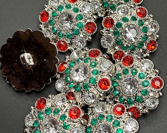 May include: A set of eight silver-toned buttons with red and green rhinestones. The buttons are round and have a raised center.