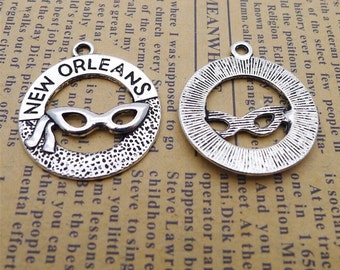 May include: Two silver charm pendants with a circle design. The first charm has the words "NEW ORLEANS" written around the circle with a pair of sunglasses inside the circle. The second charm has the word "MEANWHILE" written around the circle with a pair of sunglasses inside the circle.