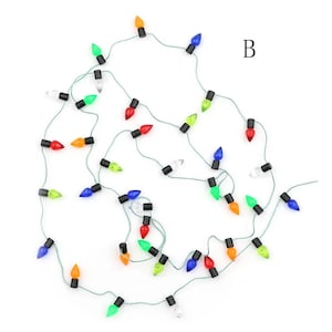 May include: A string of miniature Christmas lights with a variety of colors, including red, green, blue, orange, and clear. The lights are strung on a green wire and are arranged in a random pattern.