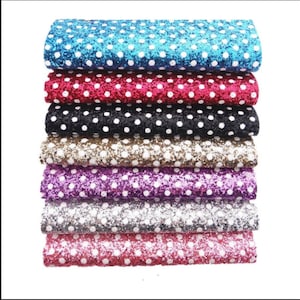 May include: A stack of eight different colored glitter fabric sheets with white polka dots. The colors are turquoise, red, black, brown, purple, silver, pink, and white.
