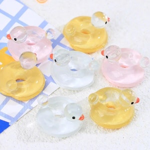 Puede incluir: Seis anillos inflables de pato en miniatura en varios colores, incluyendo amarillo, rosa y blanco. Cada anillo presenta una pequeña cabeza de pato con un pico de plástico transparente.