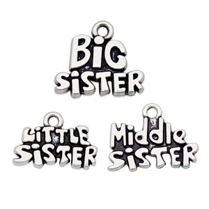 May include: Three silver charms with the words "Big Sister", "Little Sister", and "Middle Sister" in black lettering.