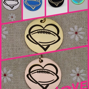May include: Five different colored metal charms in the shape of a heart with a football inside. The charms are silver, blue, black, iridescent, and rose gold.