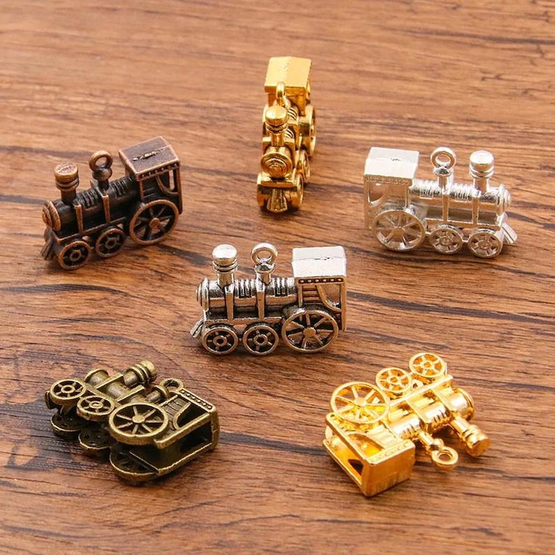 May include: Six miniature train charms in various colors, including gold, silver, and bronze. The charms are detailed with wheels, smoke stacks, and other train features. They are perfect for adding a whimsical touch to jewelry or crafts.