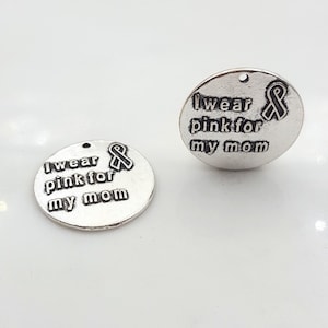 May include: Two silver metal charms with the text "I wear pink for my mom" and a pink ribbon design.