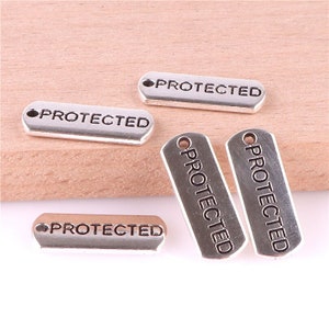 May include: Five silver-toned metal tags with the word "PROTECTED" engraved on each. The tags have a hole at the top for attaching to a chain or string.