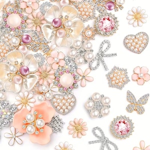 May include: An assortment of decorative embellishments in various shapes, including flowers, hearts, and bows. The embellishments feature pearls, rhinestones, and pink and white accents. The collection includes a butterfly and a variety of floral designs.
