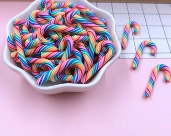 May include: A bowl filled with rainbow candy canes. The candy canes are made of a colorful, striped material and are shaped like a traditional candy cane.