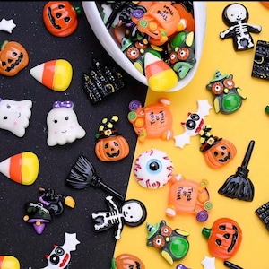 May include: A collection of small Halloween-themed resin cabochons featuring pumpkins, ghosts, skeletons, candy corn, eyeballs, owls, bats, and brooms. Some orange pumpkin pieces are printed with the text Trick or Treat in black lettering.