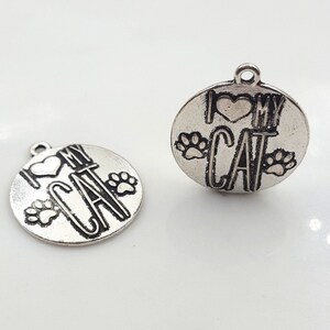 May include: Two silver charm pendants with the words "I love my cat" and paw prints.