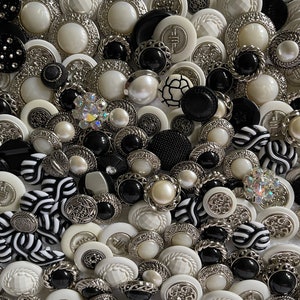 May include: A collection of black and white buttons with various designs and textures. The buttons are made of plastic, metal, and pearl. Some buttons have a silver finish, while others have a black or white finish.