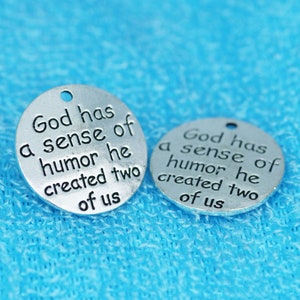 May include: Two silver metal charms with the text "God has a sense of humor he created two of us" on each charm.