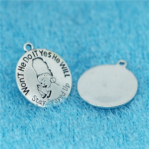 May include: Two silver charm pendants. One pendant features a praying woman with the text "Won't He Do It Yes He Will Stay Prayed Up". The other pendant is blank.