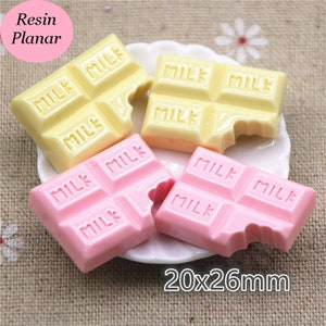 May include: Two sets of chocolate bar shaped resin charms. One set is yellow and the other is pink. Each bar has the word "MILK" printed on it. The charms are 20x26mm.