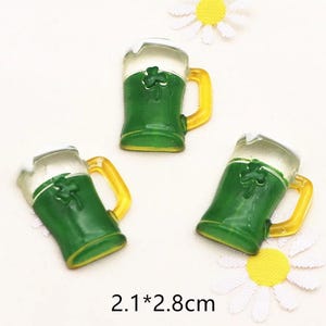 May include: Three green and white plastic beer mugs with a shamrock design. Each mug is 2.1 by 2.8 cm.