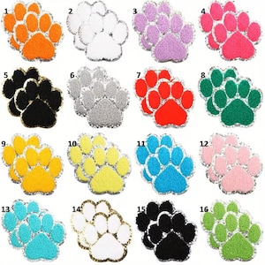 May include: A collection of sixteen colorful paw print patches. Each patch features a different color, including orange, white, purple, pink, black, gray, red, green, yellow, and blue. The patches are outlined with a silver metallic trim.