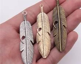 Puede incluir: Tres abalorios de plumas en plata, oro y bronce con un diseño detallado. Las plumas miden aproximadamente 5 cm de largo y tienen un agujero en la parte superior para sujetarlas a joyas.