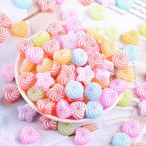 May include: A collection of colourful candy-shaped resin embellishments in various shapes, including swirls, stars, and hearts. The embellishments are perfect for adding a touch of whimsy to crafts and jewellery.